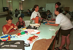 Dejanira (em pé ao fundo) dá aulas gratuitas de corte e costura para seus alunos na Vila São Pedro
