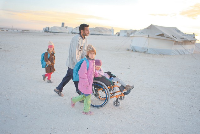 Refugiado sírio em acampamento da ONU, na Jordânia, leva as três filhas para escola da Unesco na fronteira
