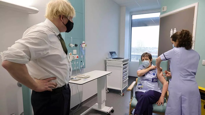 O primeiro-ministro britânico Boris Johnson observa a irmã, Susan Cole, ser imunizada com a vacina de Oxford/AstraZeneca, em visita ao Chase Farm Hospital. O uso emergencial do imunizante foi autorizado no dia 30 de dezembro